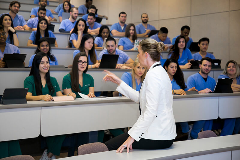 A doctor teaching a class of students wearing scrubs